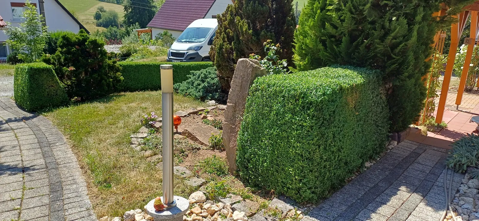 Geschnittene Büsche neben einer gepflasterten Einfahrt